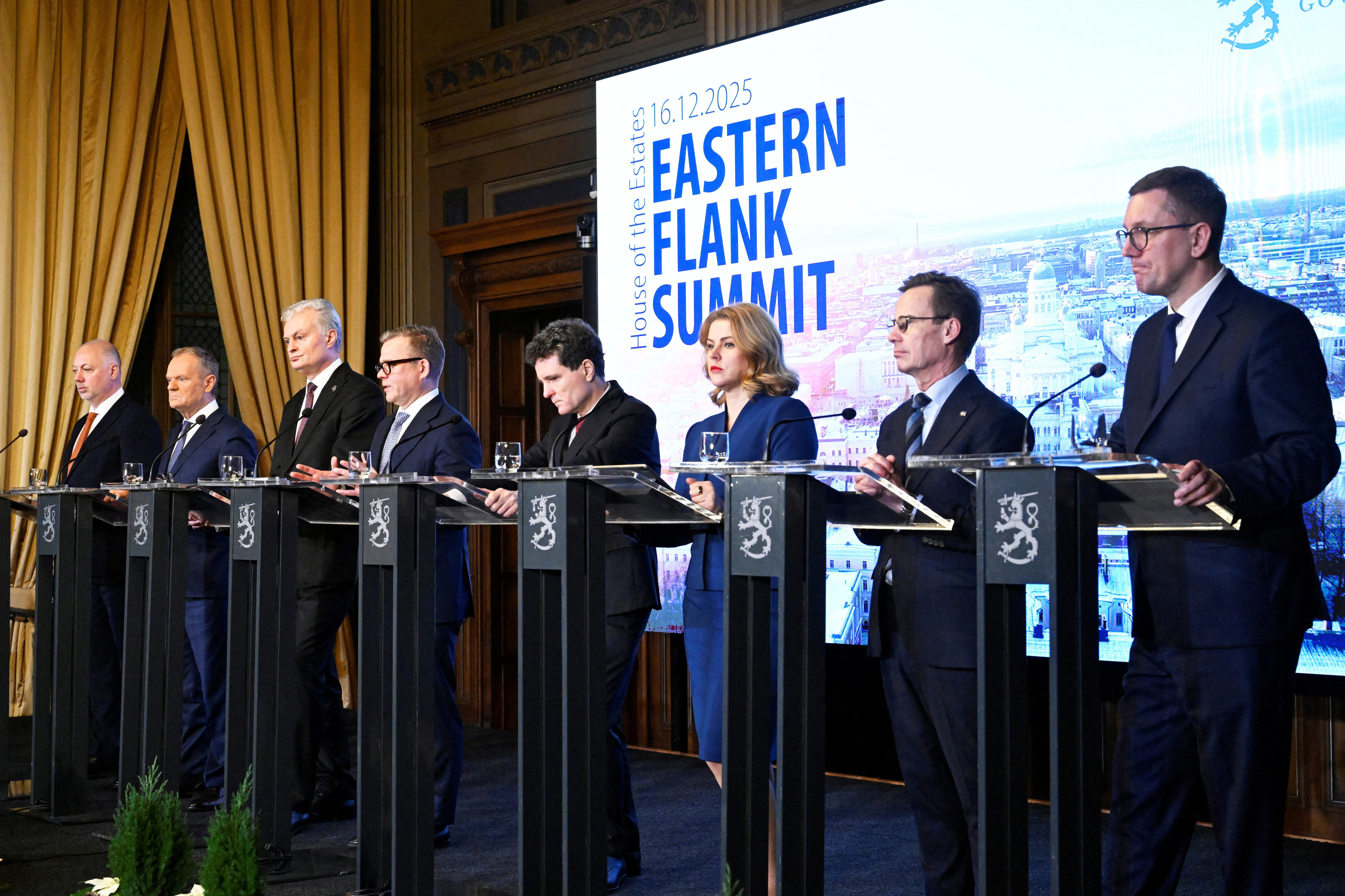 Oito líderes estão num pódio em frente a um cartaz da Cimeira do Flanco Oriental.