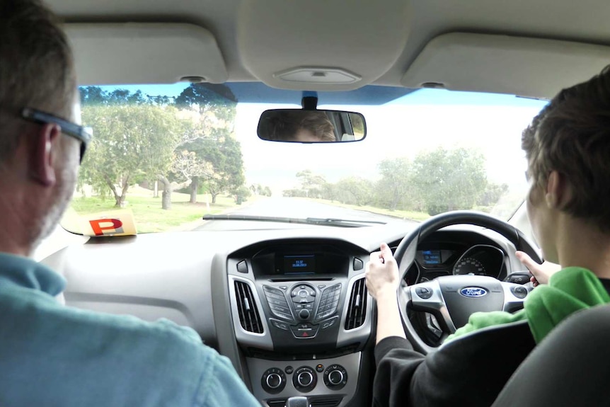 View from backseat looking out front windscreen, back of man and girl drivers' heads