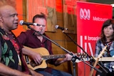 Two men and a woman perform music on a stage.