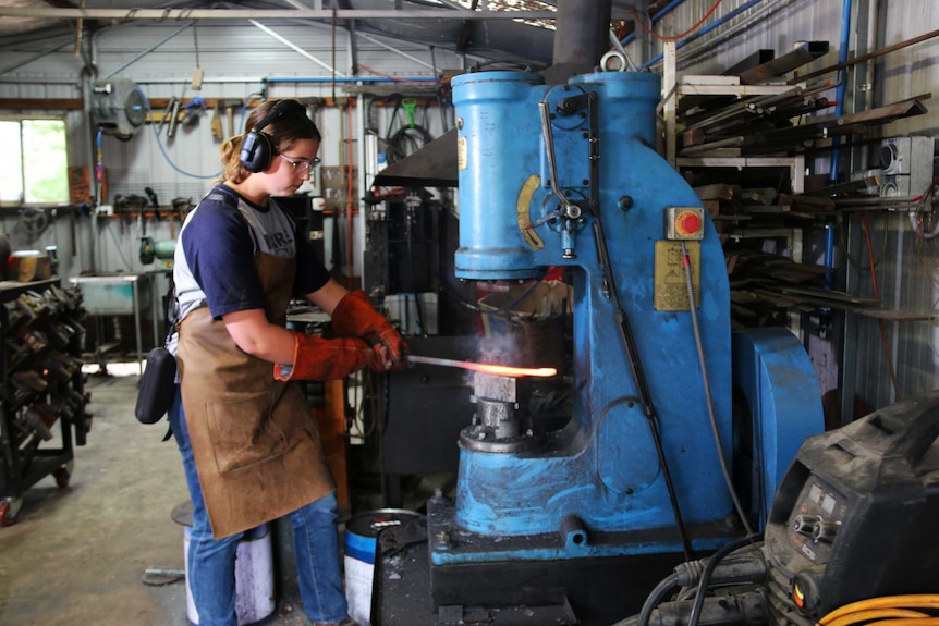 Leila Haddad using a blacksmith's power hammer to make a large knife.