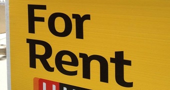 A close up view of a yellow and black 'For Rent' sign.
