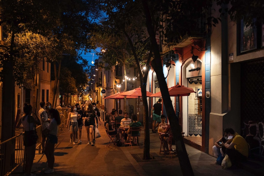 People gather outside a restaurant at night in Gracia neighborhood in Barcelona, Spain.