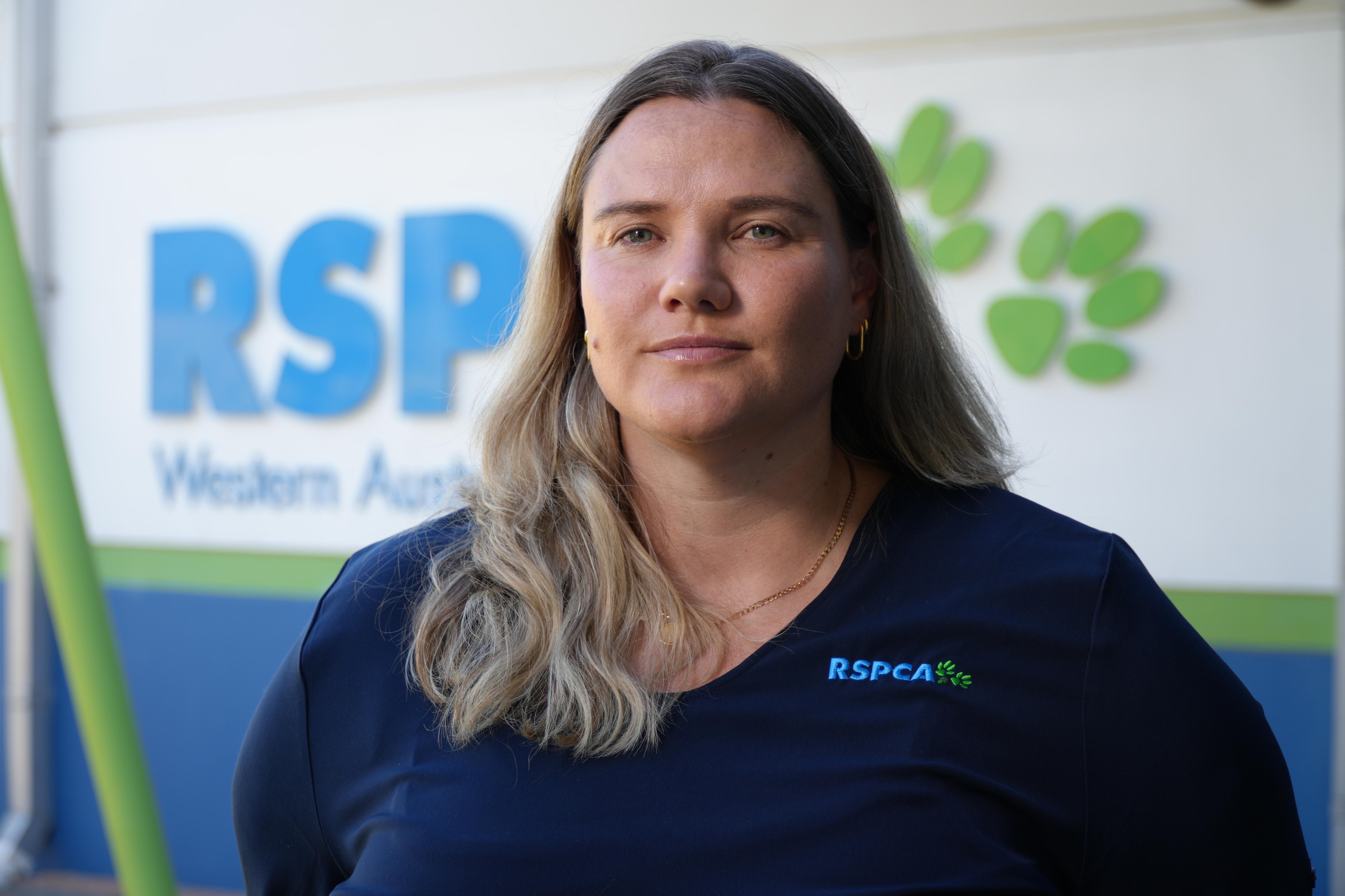 Hannah Dreaver seriously at the camera in front of an RSPCAWA sign.