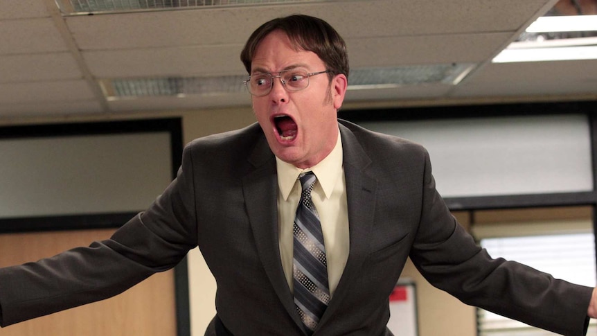 Character of Dwight from US television series The Office standing on a table screaming.