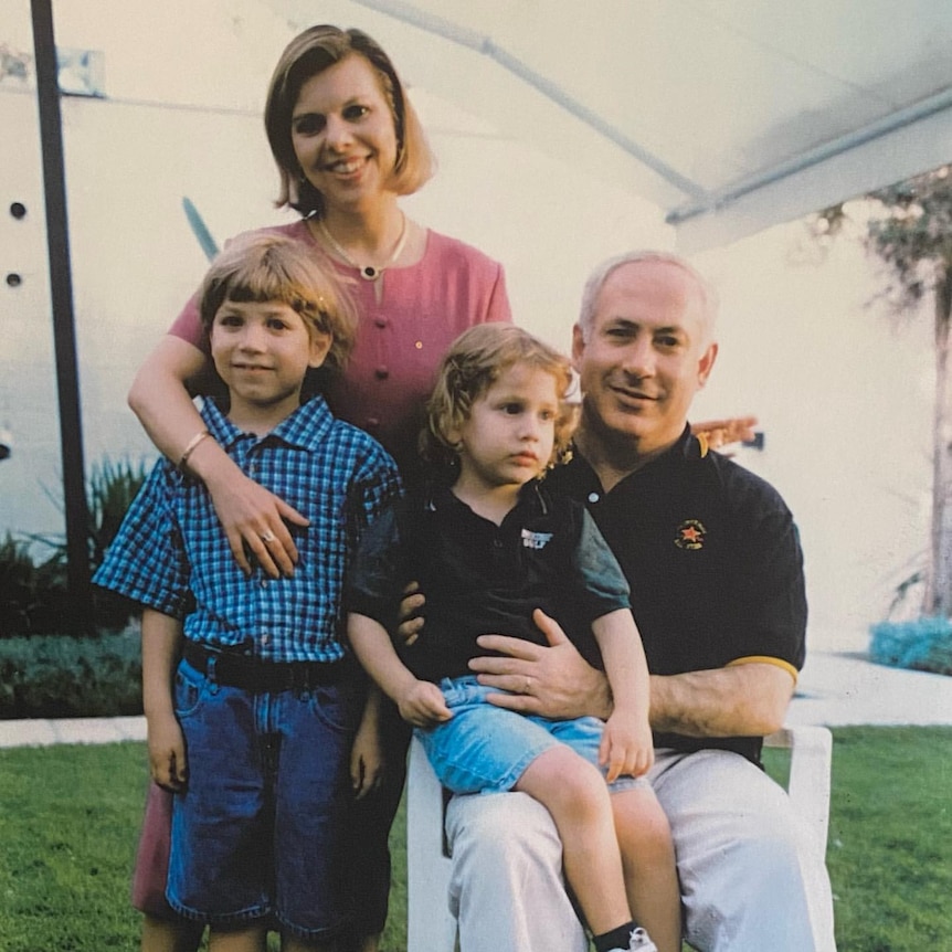 Benjamin Netanyahu with a child on his knee, another standing next to him with a woman behind