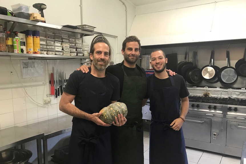 Three men together in a kitchen