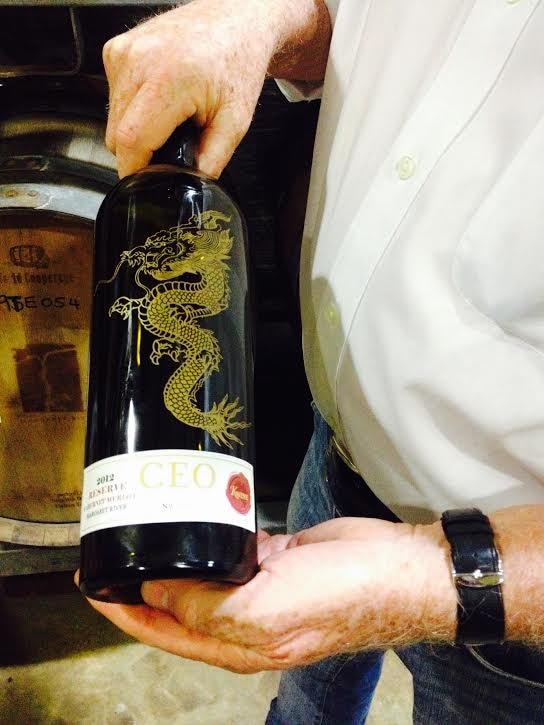 A close up of a man holding a wine bottle with a dragon on the label.