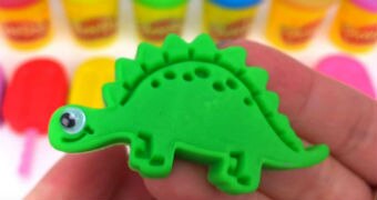 A pair of hands holds a green plasticine dinosaur.