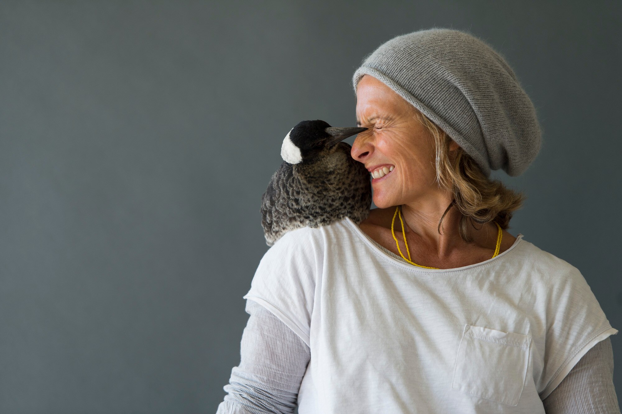 An Australian para surfer smiling with a magpie on her right shoulder.