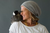 An Australian para surfer smiling with a magpie on her right shoulder.