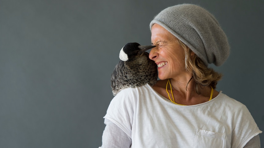 An Australian para surfer smiling with a magpie on her right shoulder.