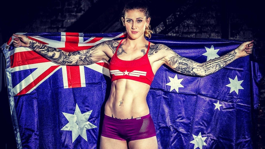 UFC fighter Megan Anderson has arms spread holding an Australian flag.