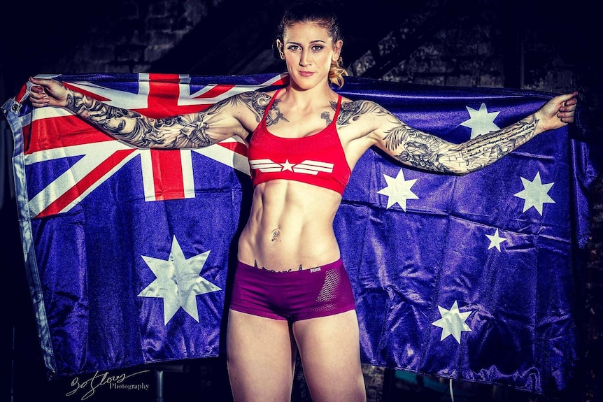 UFC fighter Megan Anderson has arms spread holding an Australian flag.