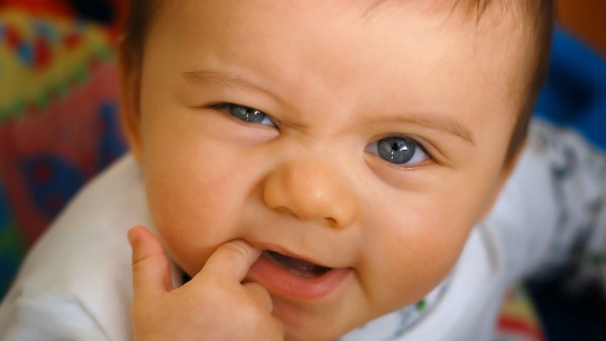 Close-up of cute baby's face with finger in mouth