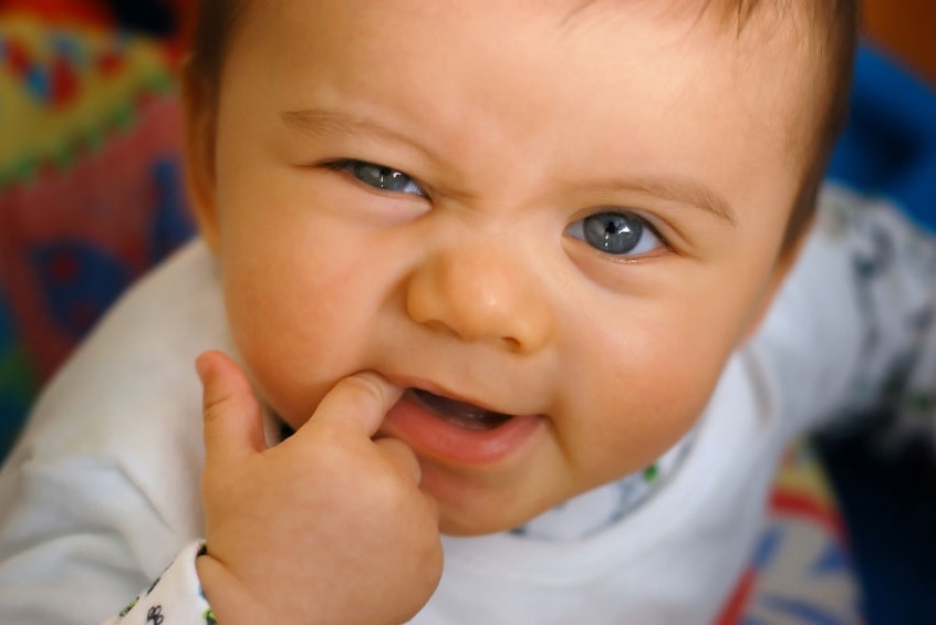 Close-up of cute baby's face with finger in mouth