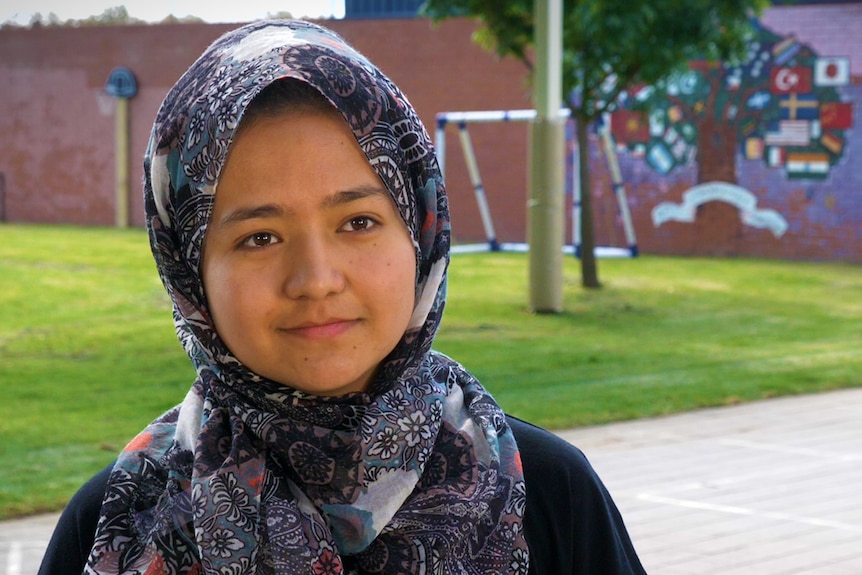 Afghan teenager smiling at camera with head scarf