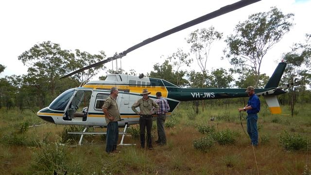 A group of university researchers stand in front of a helicopter in Nitmiluk National Park.