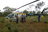 A group of university researchers stand in front of a helicopter in Nitmiluk National Park.