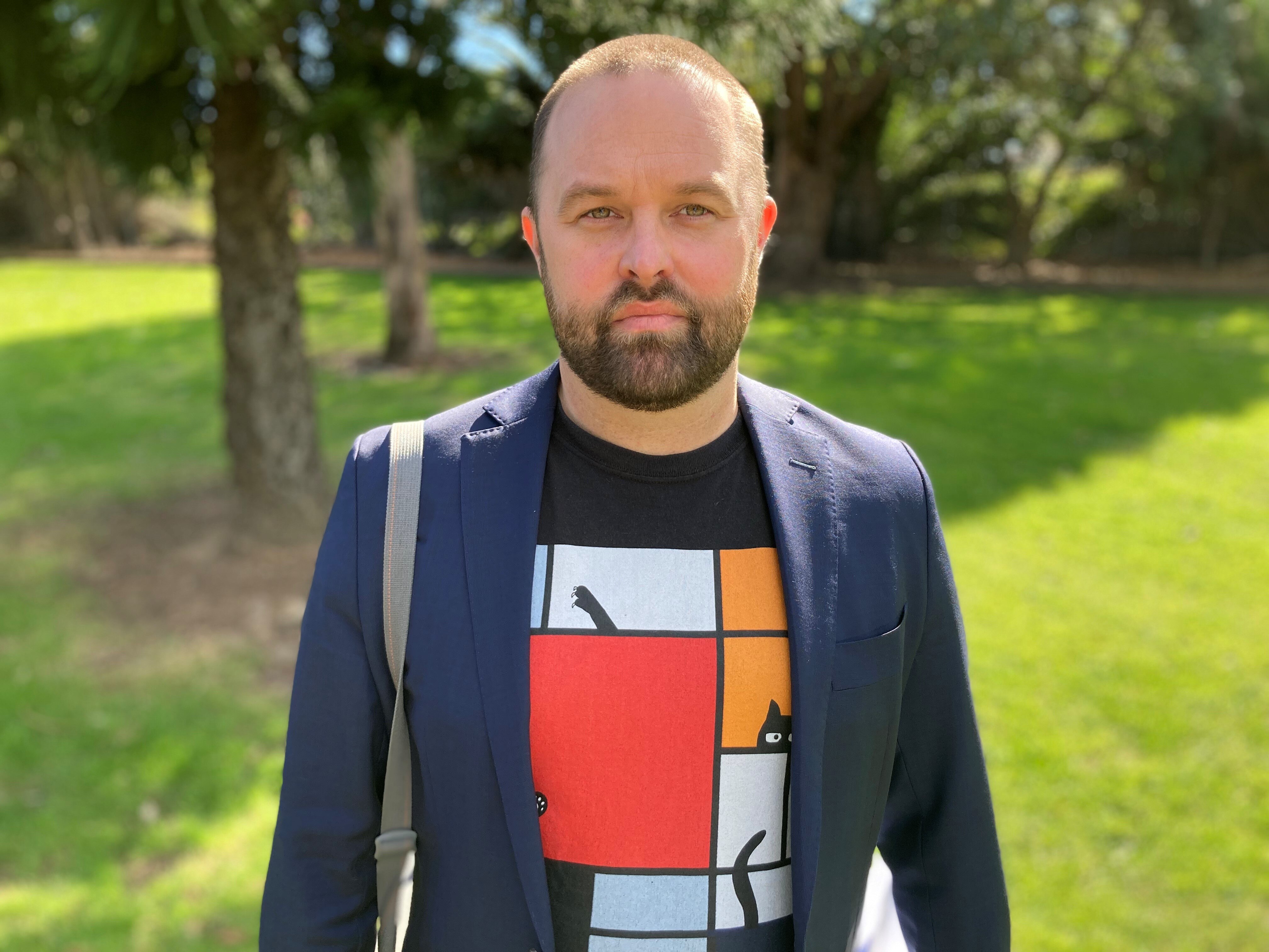 Dr Troy Henderson stands in a park in the sunshine.