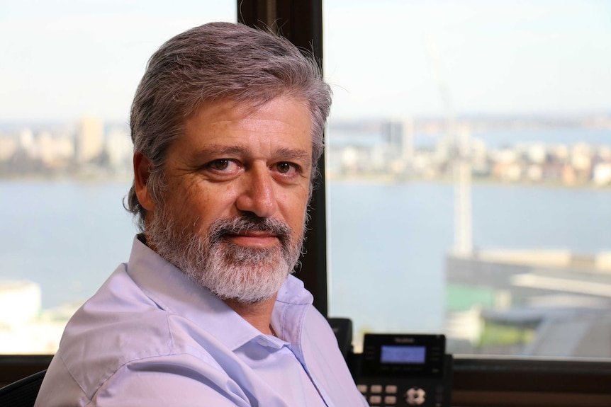 Mr Moreno sits at a desk with a view of the Swan River behind him.