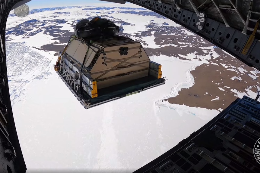 Shot from the plane's interior, a large case of supplies is airdropped down to Antarctica.