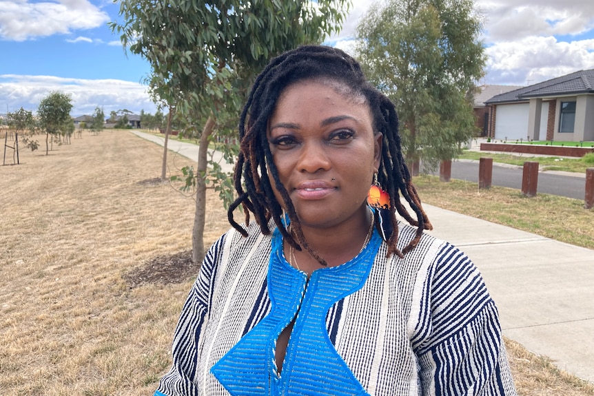 Joyce Toway stands in a grassy park opposite residential houses.