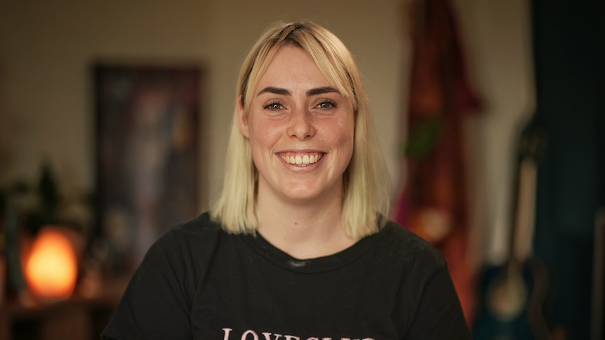 A portrait of Lily Mitchell smiling wearing a black shirt with 'loveclub' written on the front.