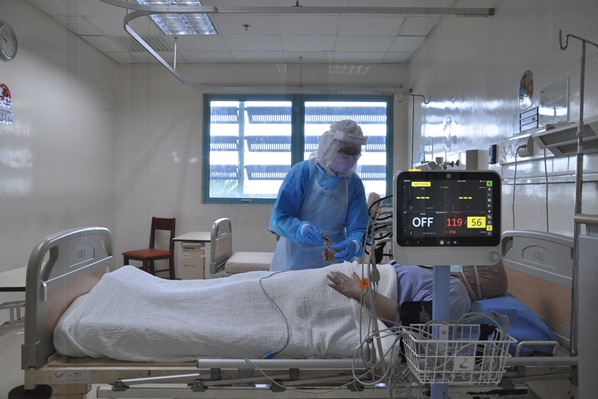 A doctor checks a patient's condition inside an infectious disease isolation room