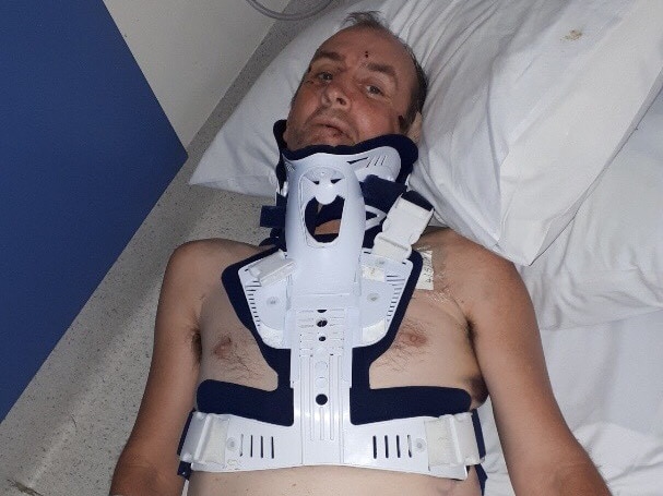 Man in neck brace lying on hospital bed