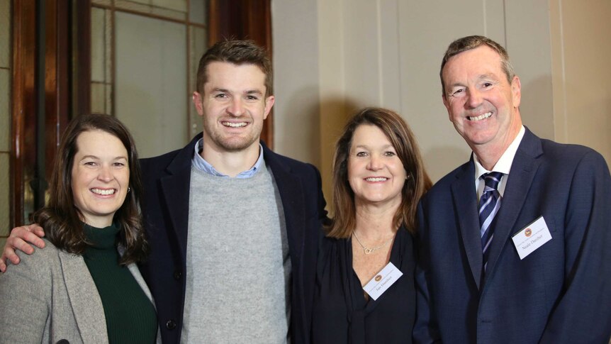 Neale Daniher and three of his family members smile happily at the camera.