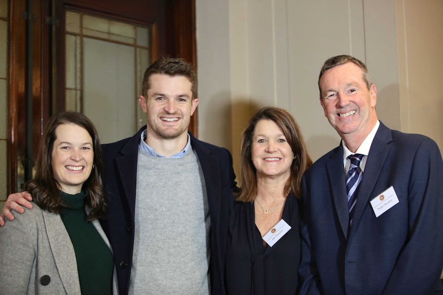 Neale Daniher and three of his family members smile happily at the camera.