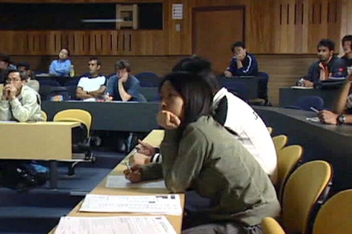 TV still of students (probably university) sitting in a classroom.