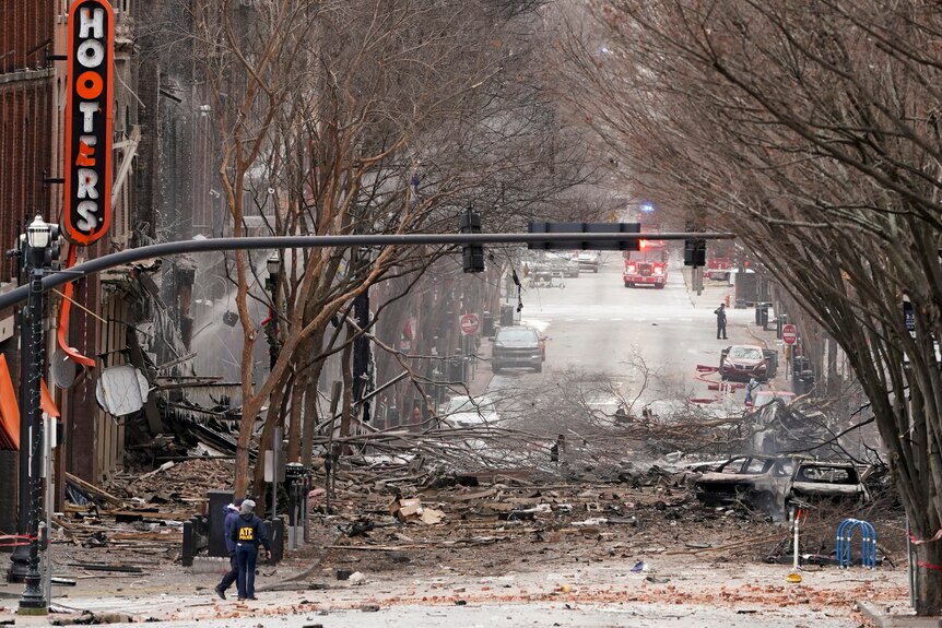 People walk in the wreckage of an explosion in a city street.