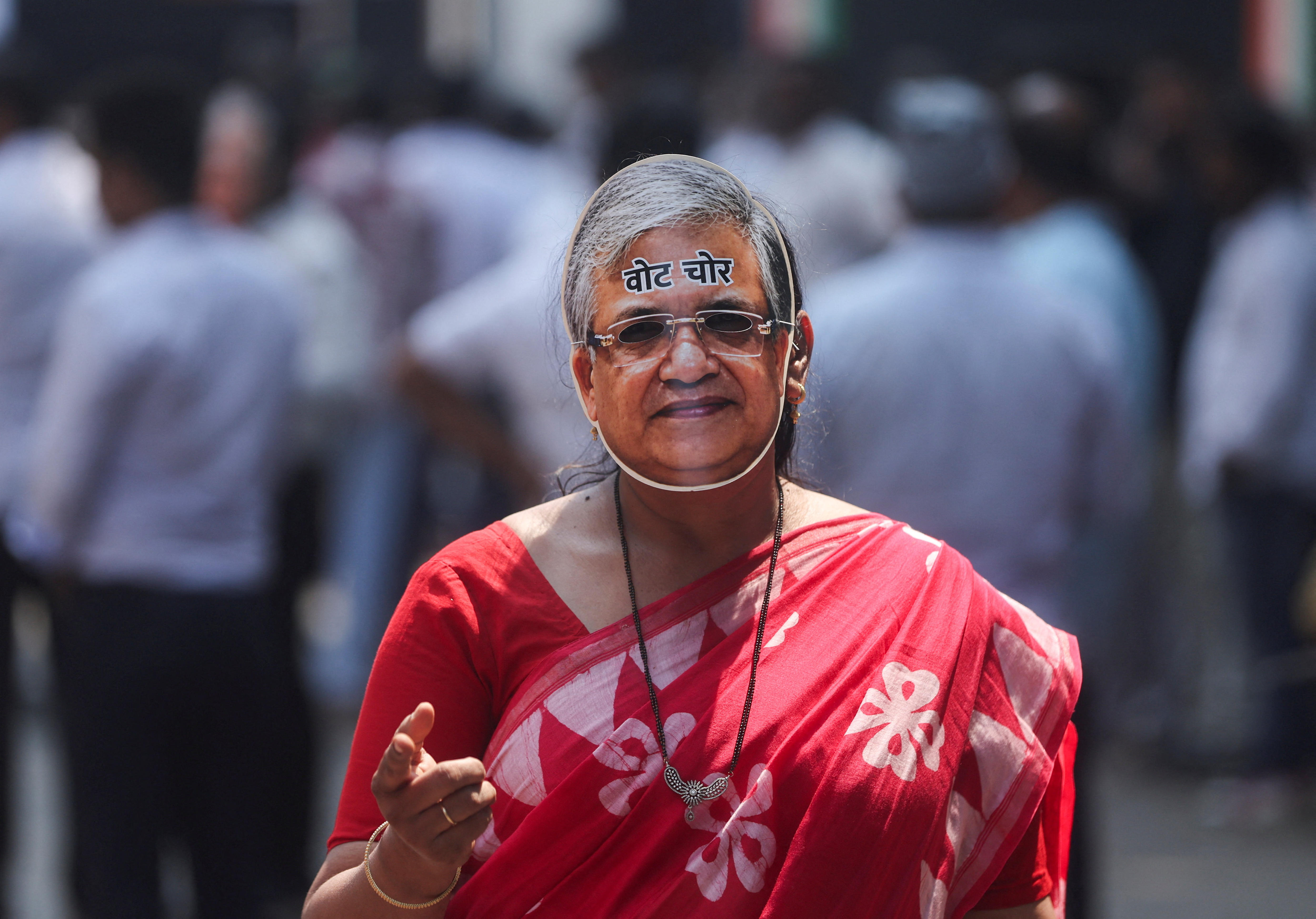 A protester wearing a mask of the face of Indian Chief Election commissioner with the words "vote thief" written on it.