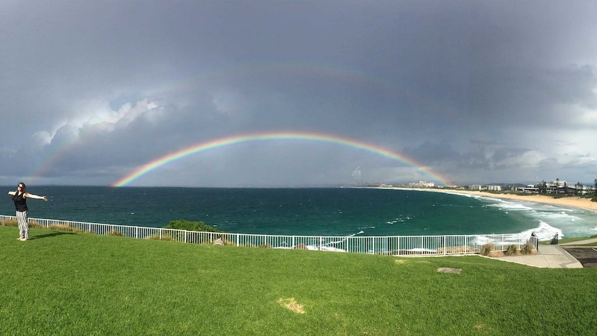 A woman shows her delight after seeing a rainbow form over the beach at South Wollongong.