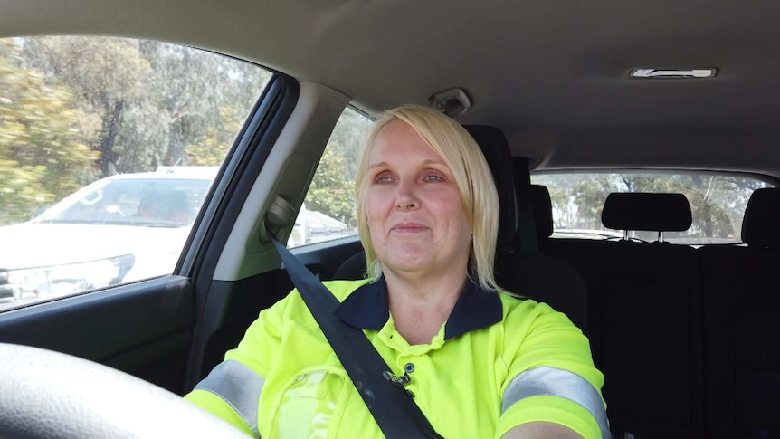 Desiree Sheets-Chavolla driving to work in her car wearing a high vis vest