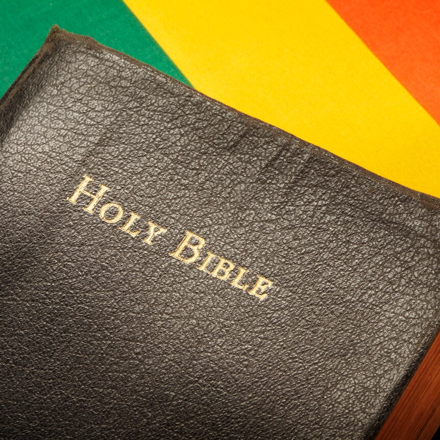 A Holy Bible sitting on top of a rainbow flag