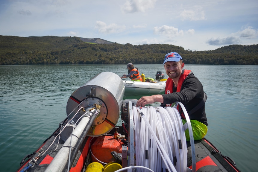 Jamie on a small boat with drilling equipment. 