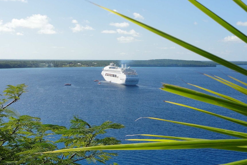 The Pacific Dawn is seen at seen in this photo taken from Lifou island, New Caledonia. Green foliage is seen in the foreground.