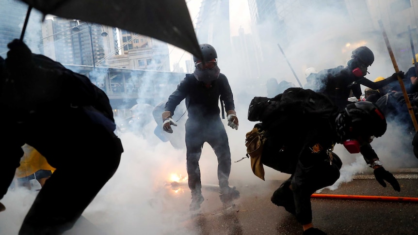 A cloud of smoke and flames engulf a road as protesters duck for cover