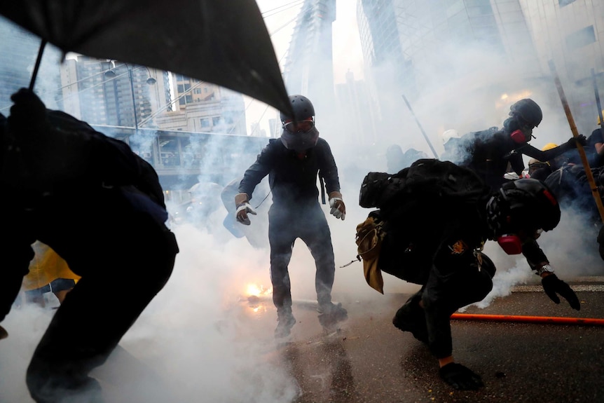 A cloud of smoke and flames engulf a road as protesters duck for cover