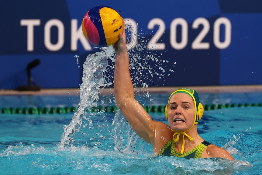 An Australian female water polo player holds the ball as she prepares to pass against Canada.