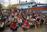 Burmese slave fishermen sitting in front trawlers vote to return home after being rescued in the Aru Islands, Indonesia