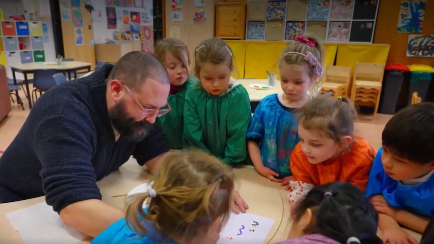 Children in a classroom watching a teacher drawing
