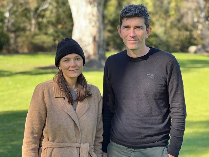 A man and a woman wearing winter clothes in a park