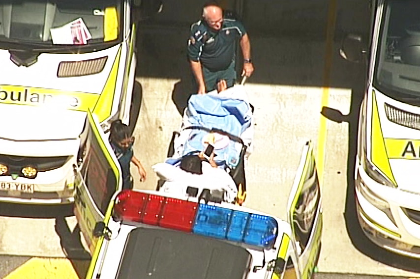 Aerial image of university student Yang Chen being taken out of an ambulance on a stretcher at Robina Hospital.
