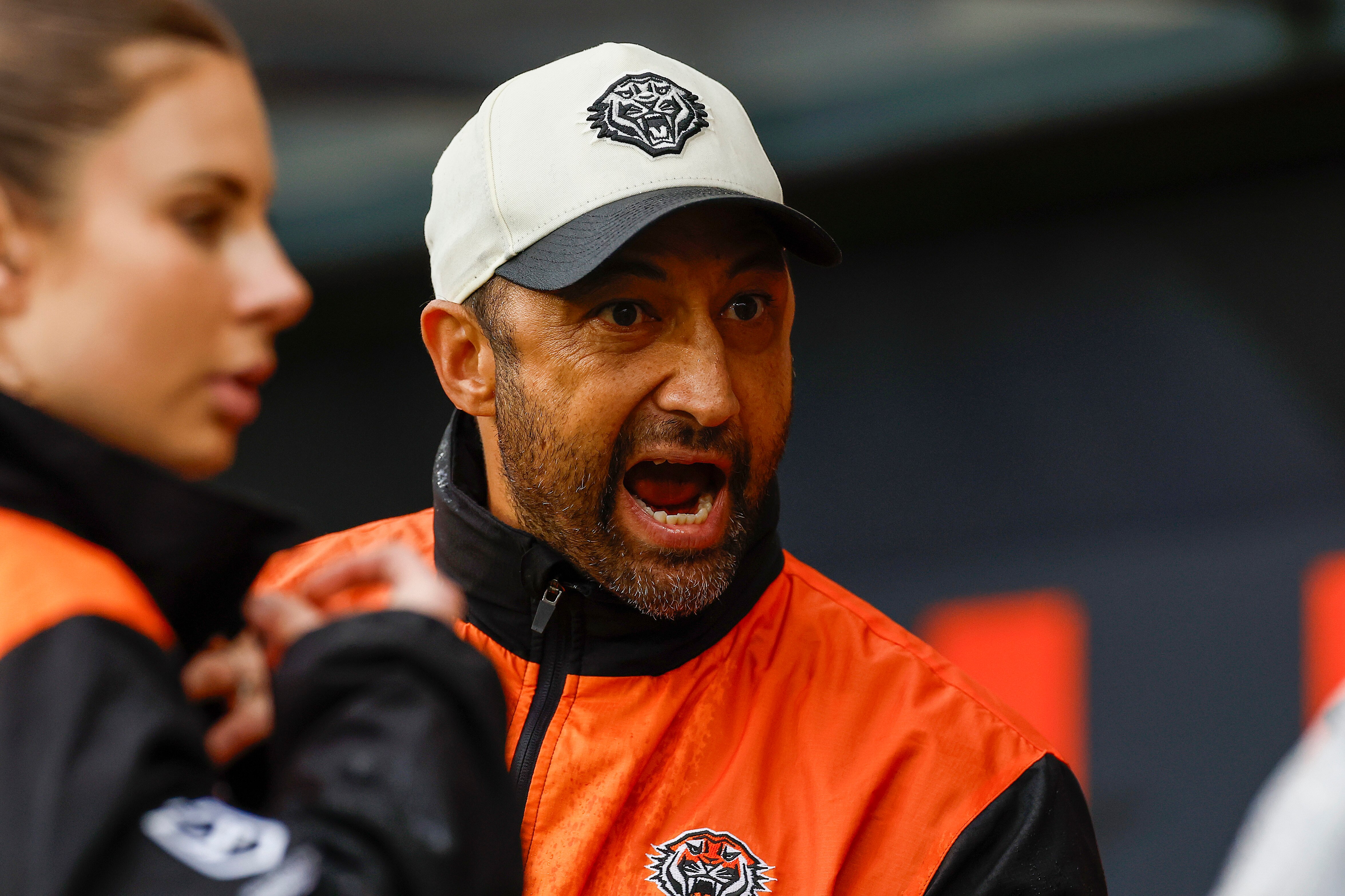 grita un hombre en ropa deportiva mientras está al margen de un partido de los Wests Tigers.