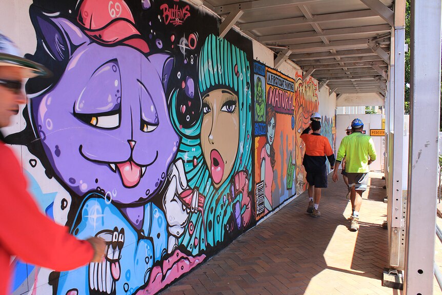 Construction workers walk past the 'sugar jam' murals in early 2016