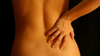 Woman with her hand on her lower back.