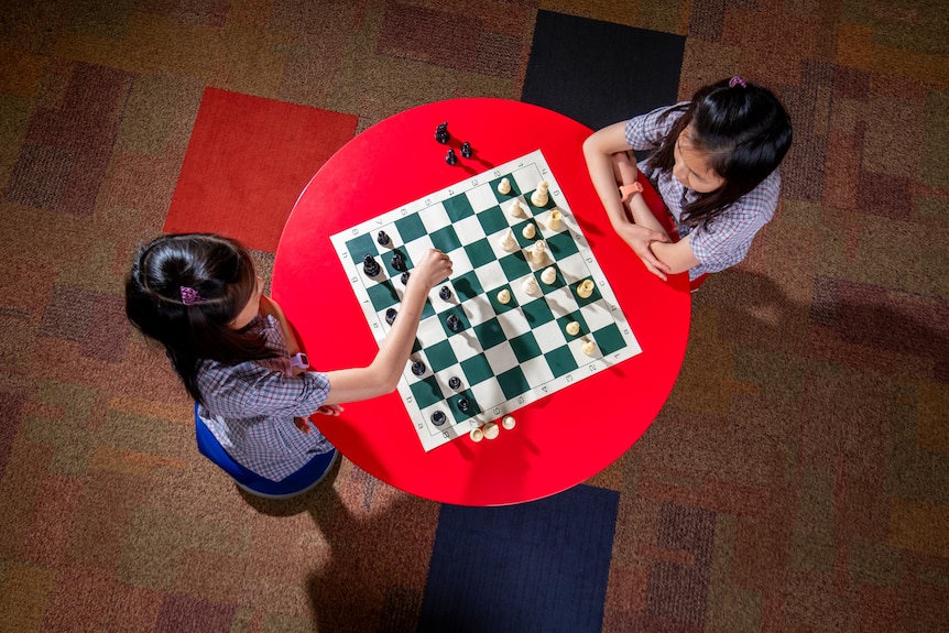 Two girls play chess.
